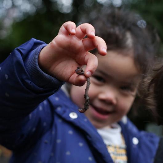Girl holding up a worm from the nursery wormery