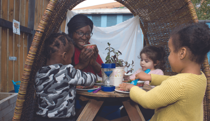 Staff member playing at having tea in a den in the garden